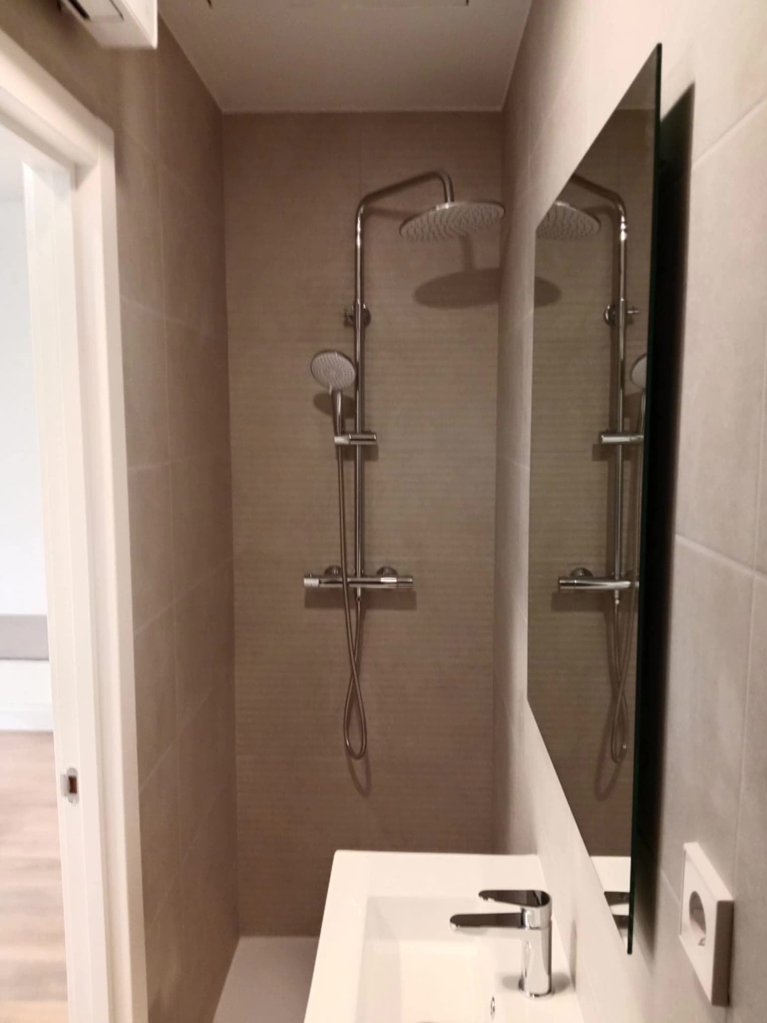 Ducha reformada con rociador de techo, espejo y lavabo