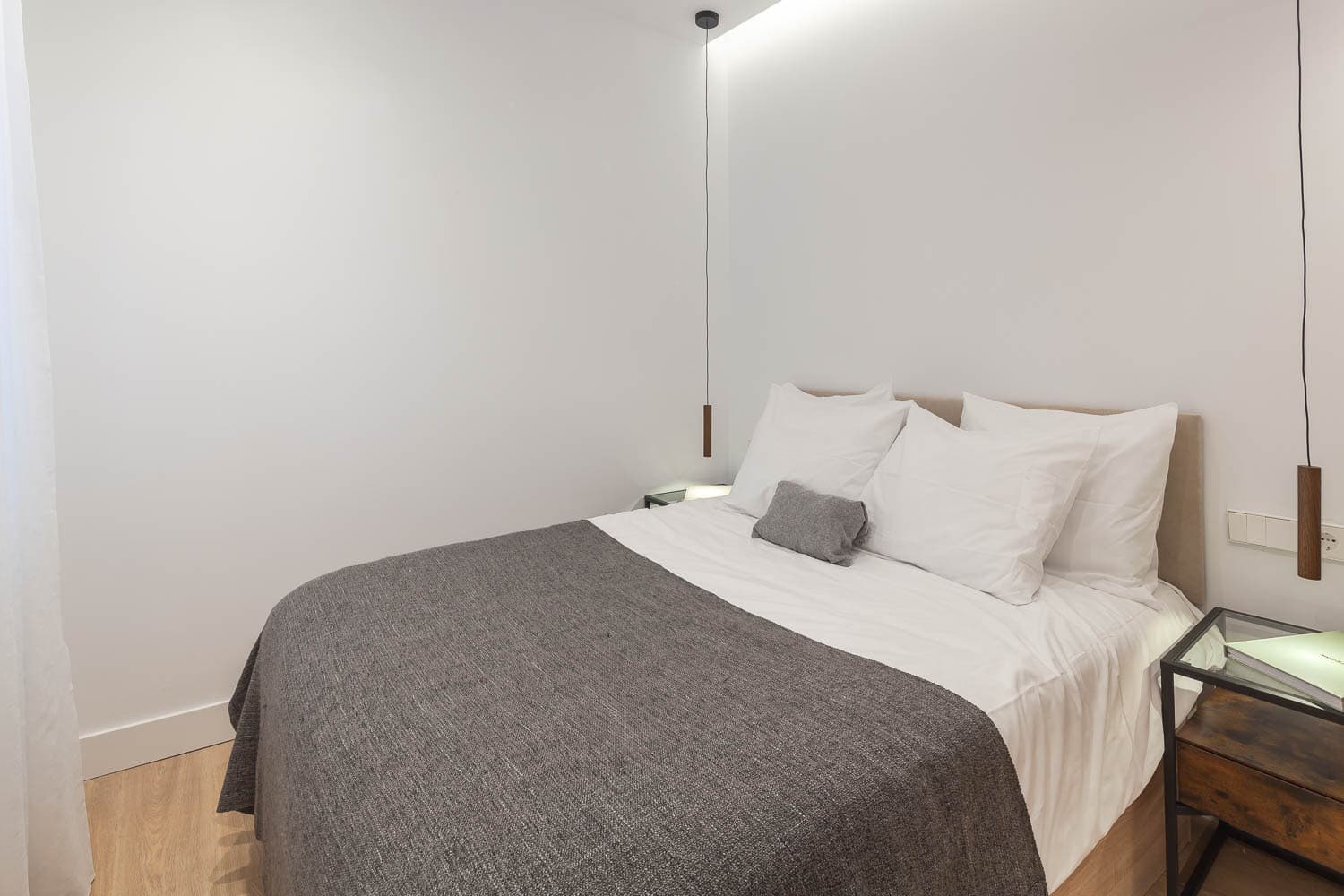Dormitorio con lámparas colgantes a ambos lados de la cama. Cisneros, Madrid.