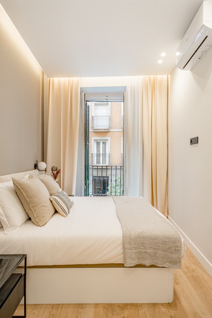 Dormitorio con balcón a la calle y cortinas de suelo a techo. Divino Pastor 14, Madrid.