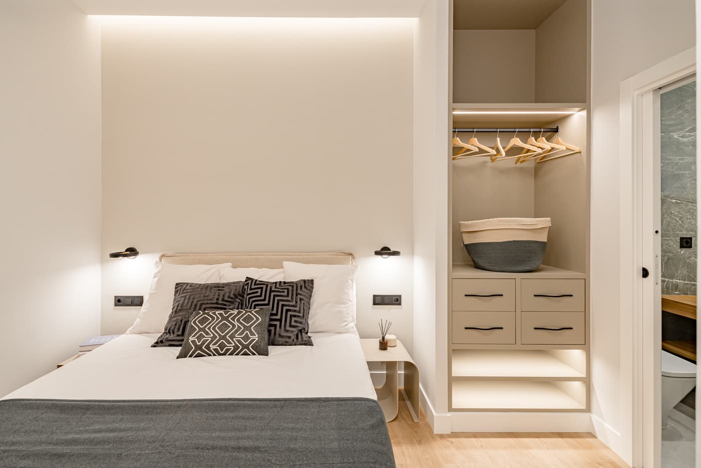 Dormitorio con hornacina iluminada sobre la cama y armario abierto a medida. Divino Pastor 14, Madrid.