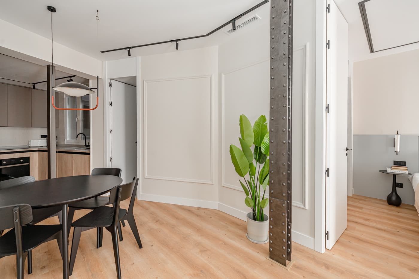 Comedor visto desde la cocina, con la columna de acero vista y la puerta del dormitorio abierta. Hermosilla 133, Madrid.