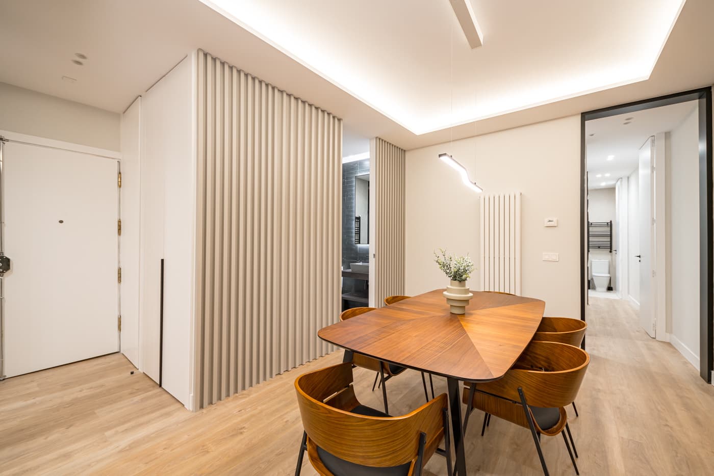 Comedor junto a la entrada, separado por una celosía de lamas verticales. Jesús del Valle 25, Madrid.