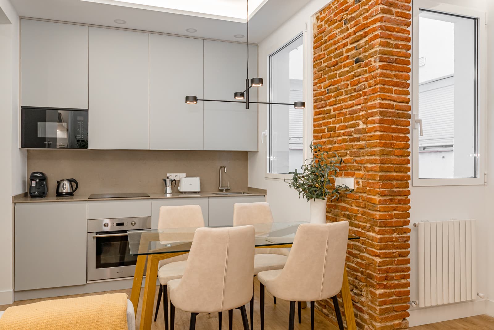 Cocina y comedor con un pilar de ladrillo visto junto a la ventana. Lagasca 136, Madrid.