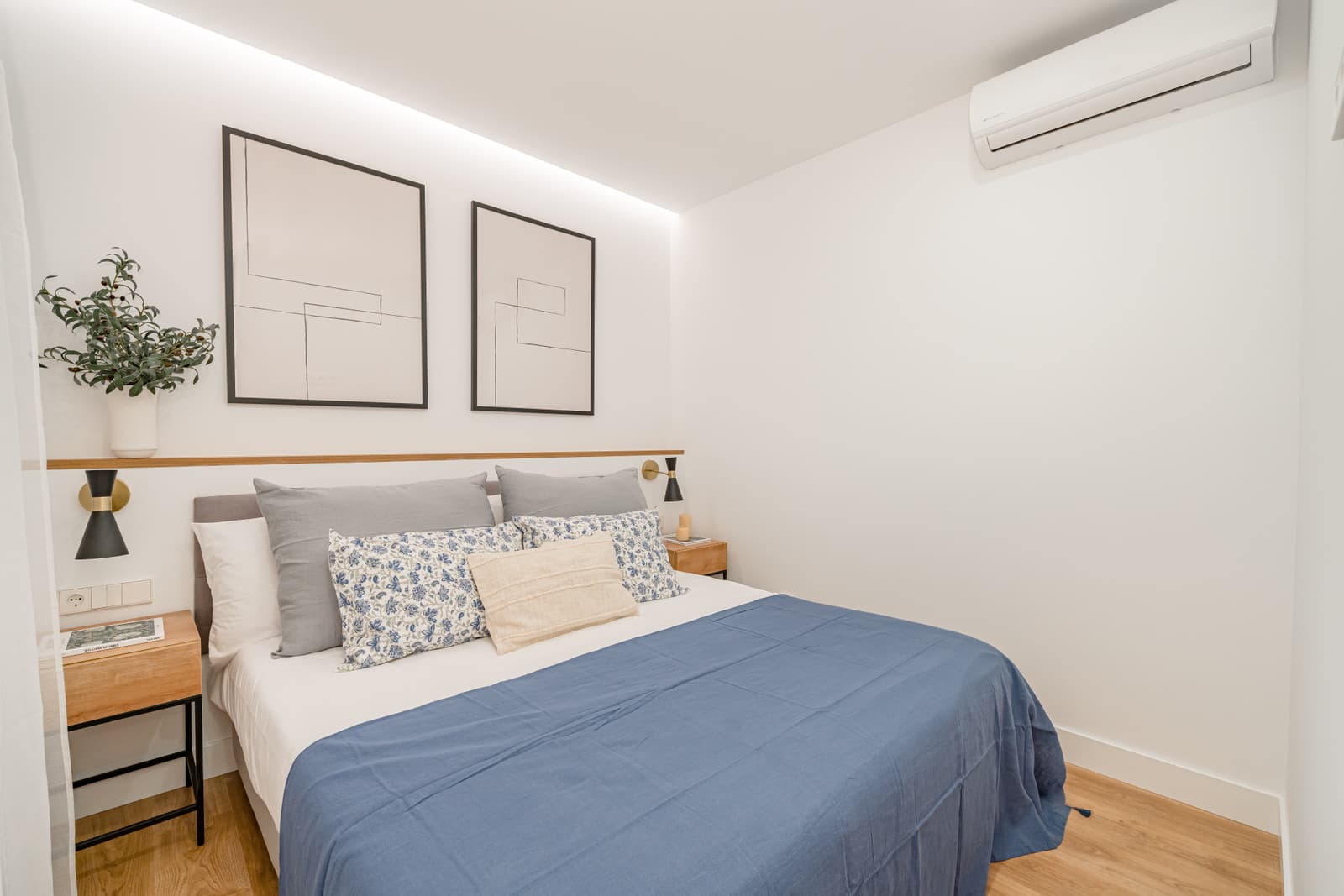 Dormitorio con luz indirecta en el techo y dos láminas enmarcadas sobre el cabecero. Lagasca 136, Madrid.