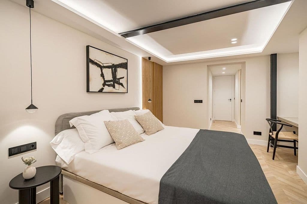 Dormitorio principal con foseado iluminado y un perfil negro visto en el techo. Mayor 73, Madrid.