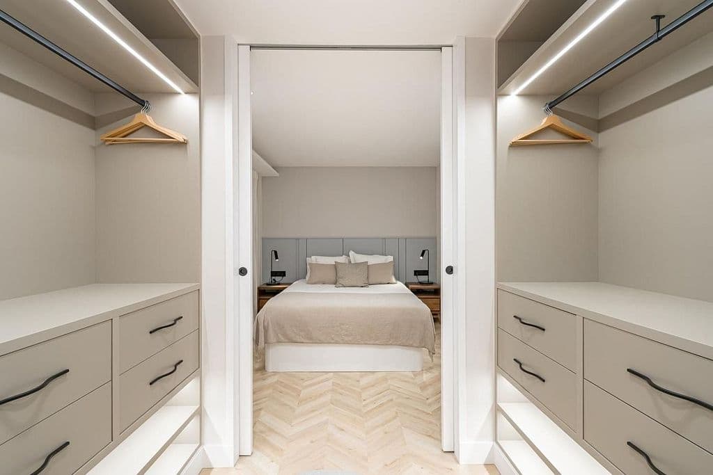 Vestidor de paso con cajoneras a ambos lados y puertas correderas abiertas al dormitorio. Mayor 73, Madrid.
