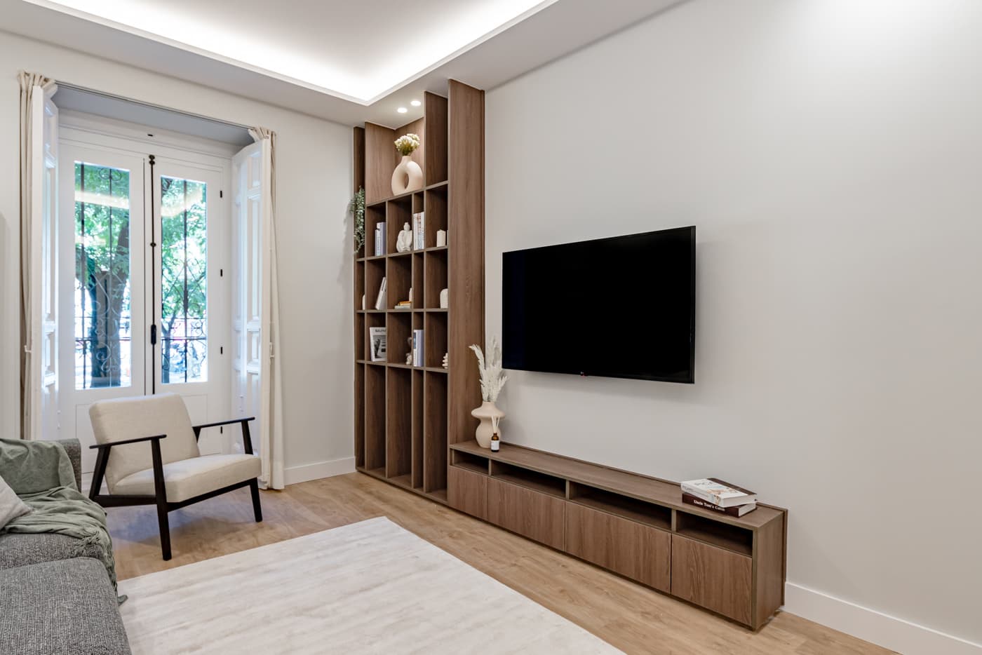 Salón con balcón, butaca y mueble a medida con librería. Plaza de Santa Bárbara 6, Madrid.