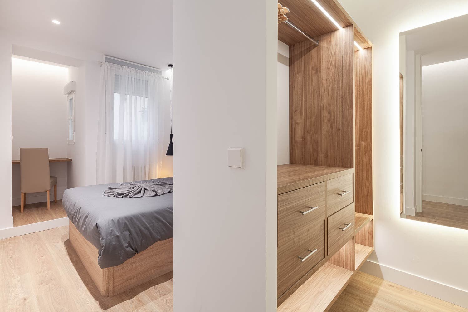 Dormitorio y vestidor en acabado madera con espejo retroiluminado. Calle Ruiz, Madrid.