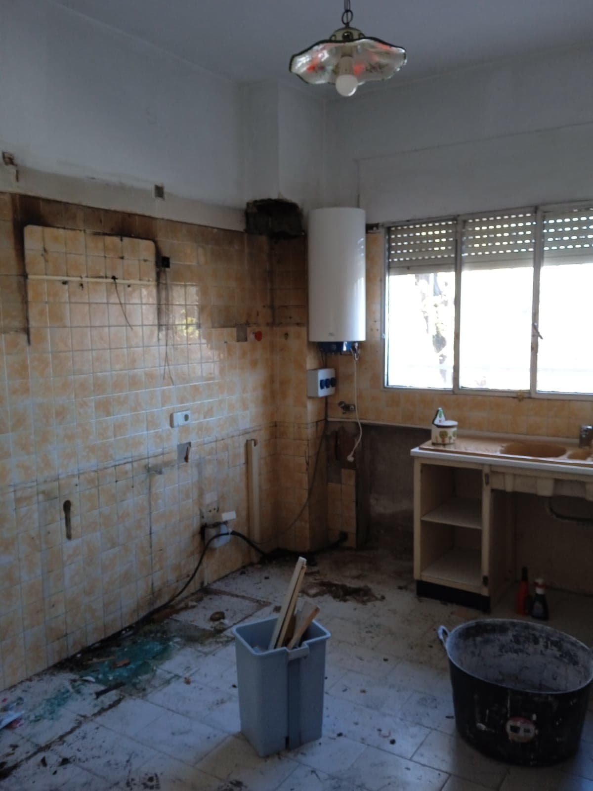La cocina antes de la obra, desmontada, con el calentador en la pared y los muebles fuera.
