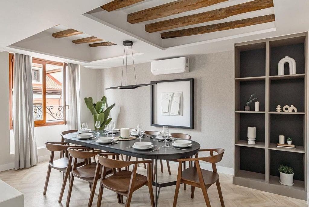 Comedor con vigas de madera vistas en el techo y mesa ovalada
