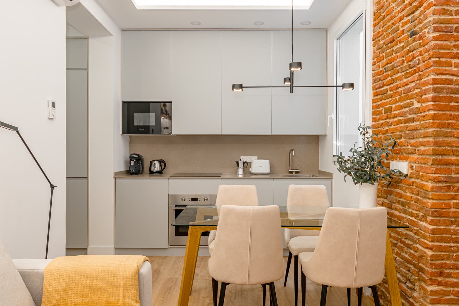 Cocina abierta al comedor con pared de ladrillo visto