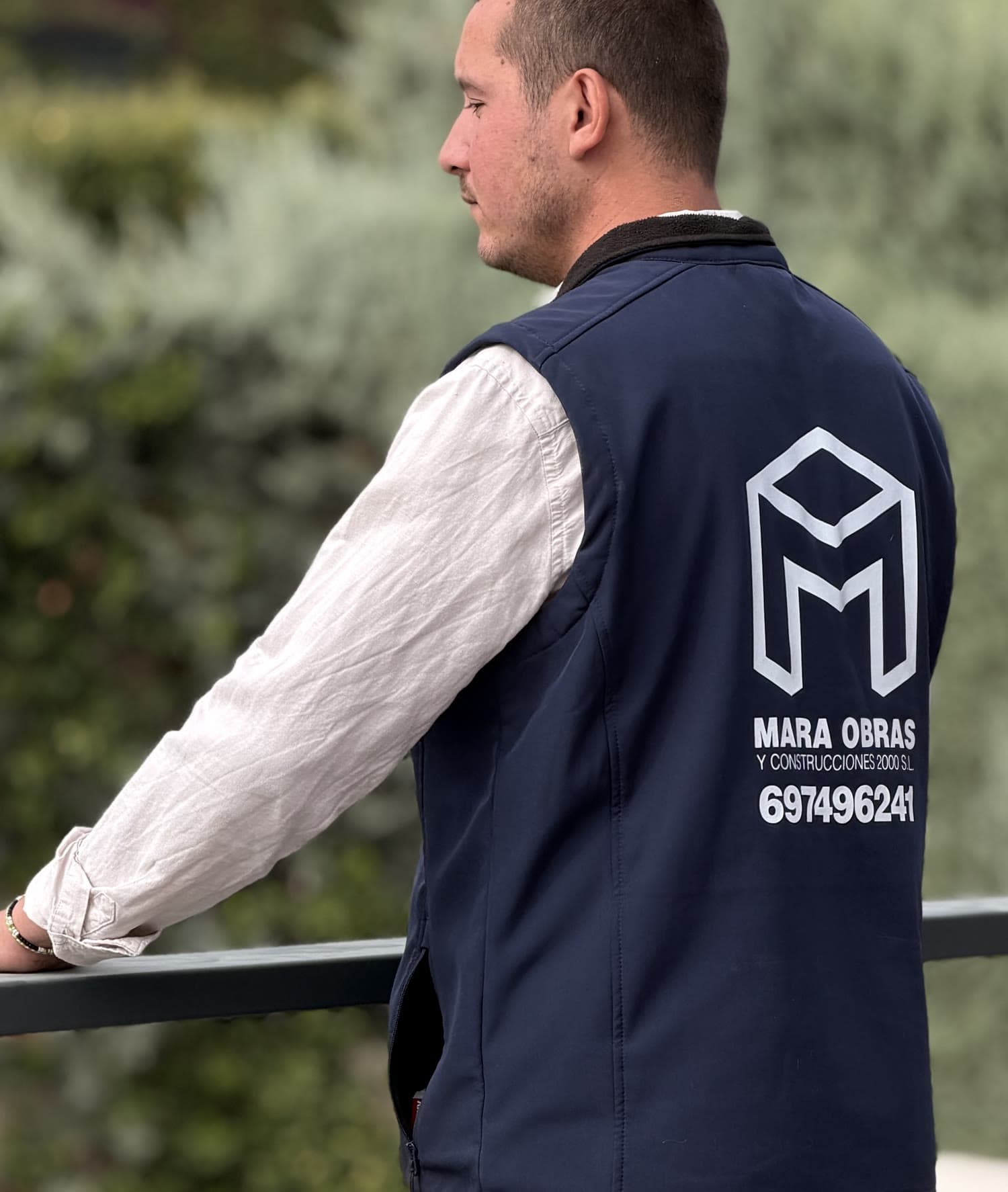 Persona del equipo de Mara Obras con el chaleco de la empresa, apoyada en la barandilla de la terraza.