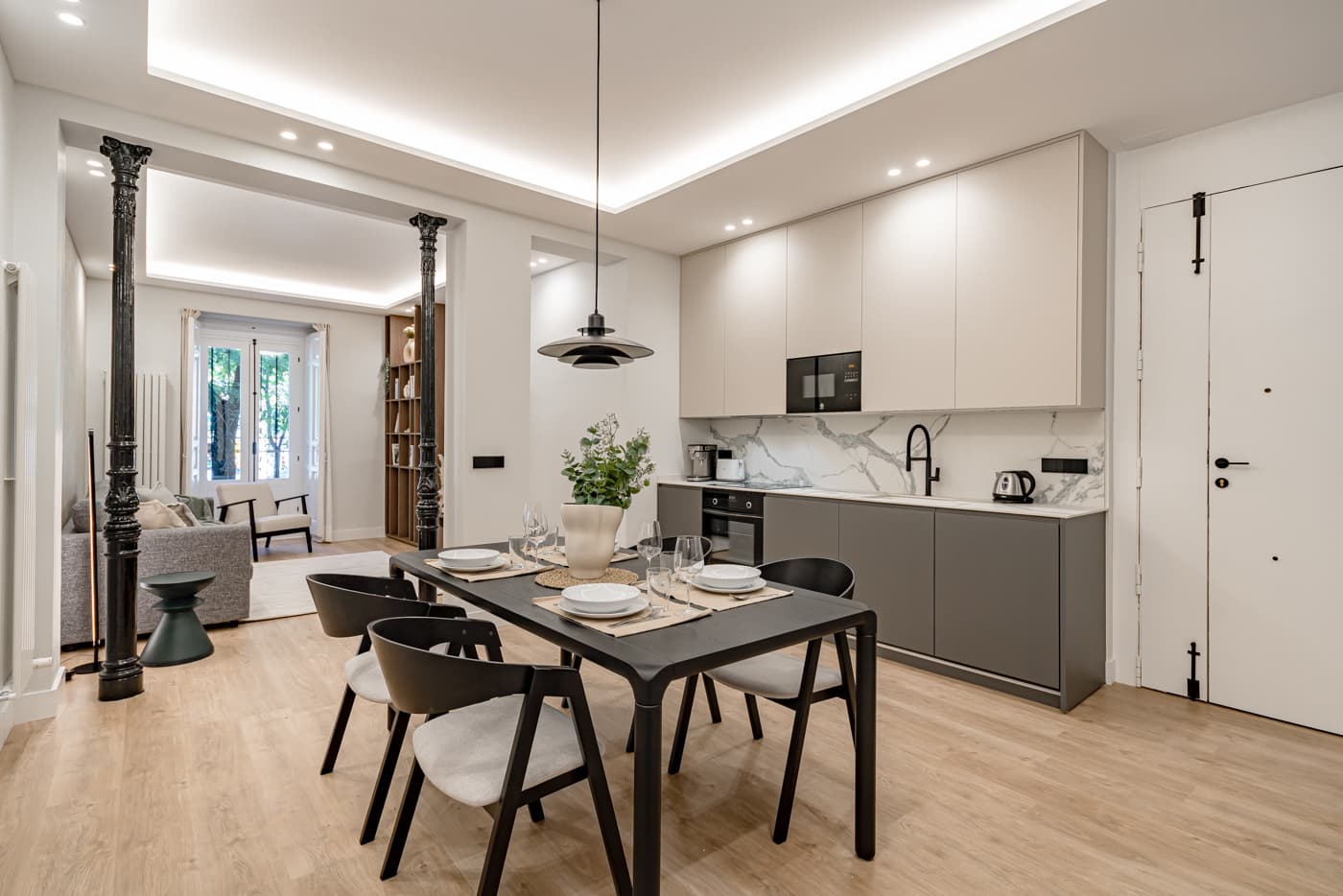 Cocina y comedor en un mismo espacio; a la izquierda, dos columnas de hierro negras marcan el paso al salón. Plaza de Santa Bárbara 6, Madrid.