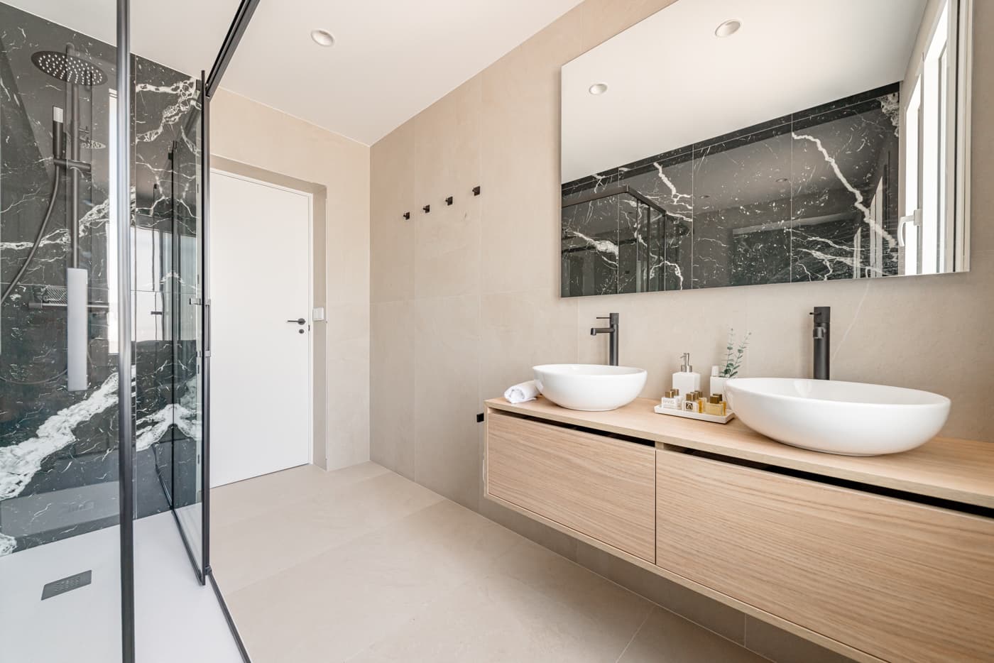 Baño con dos lavabos sobre mueble suspendido en acabado madera y ducha con mampara. Vía Complutense, Alcalá de Henares.