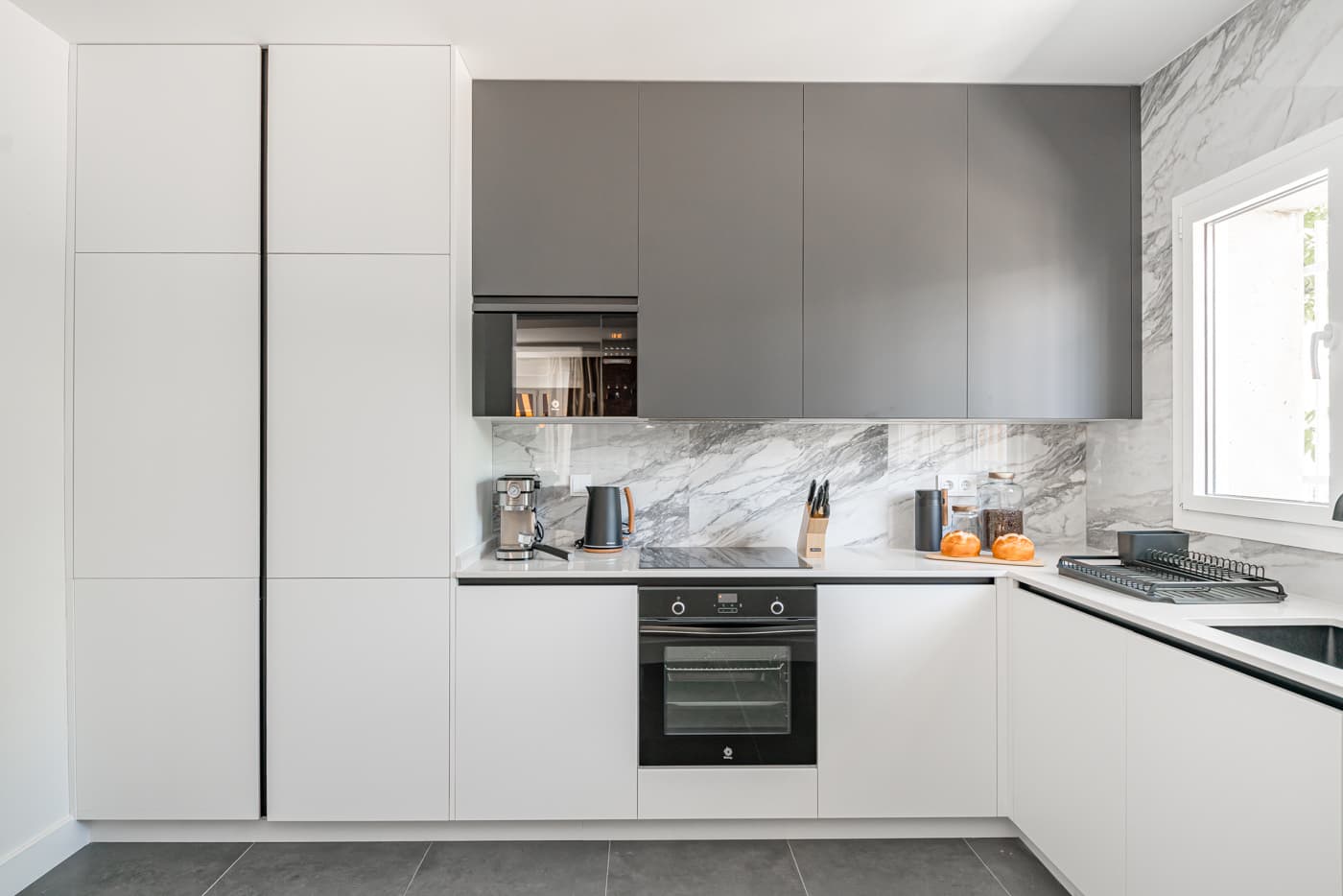 Cocina blanca con muebles altos grises y frente veteado. Vía Complutense, Alcalá de Henares.