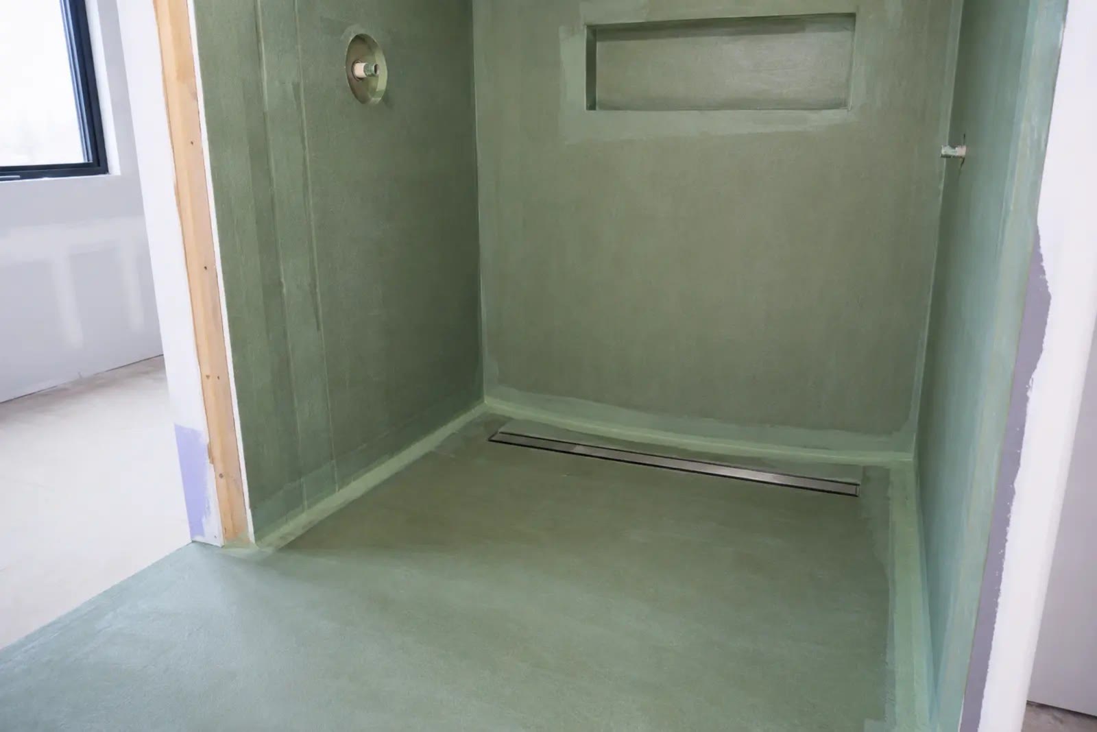 Ducha de obra con impermeabilización continua, refuerzo de esquinas y desagüe lineal