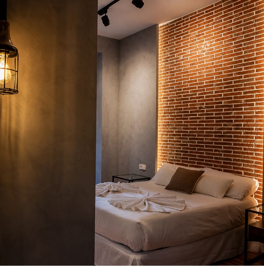 Dormitorio con pared de ladrillo visto e iluminación cálida, proyecto del Estudio Conti&Rodriguez
