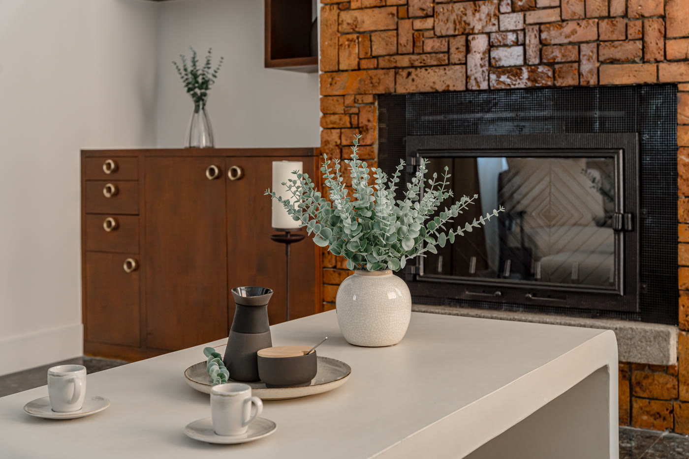 Cocina con chimenea revestida de piedra, mueble de madera y barra blanca